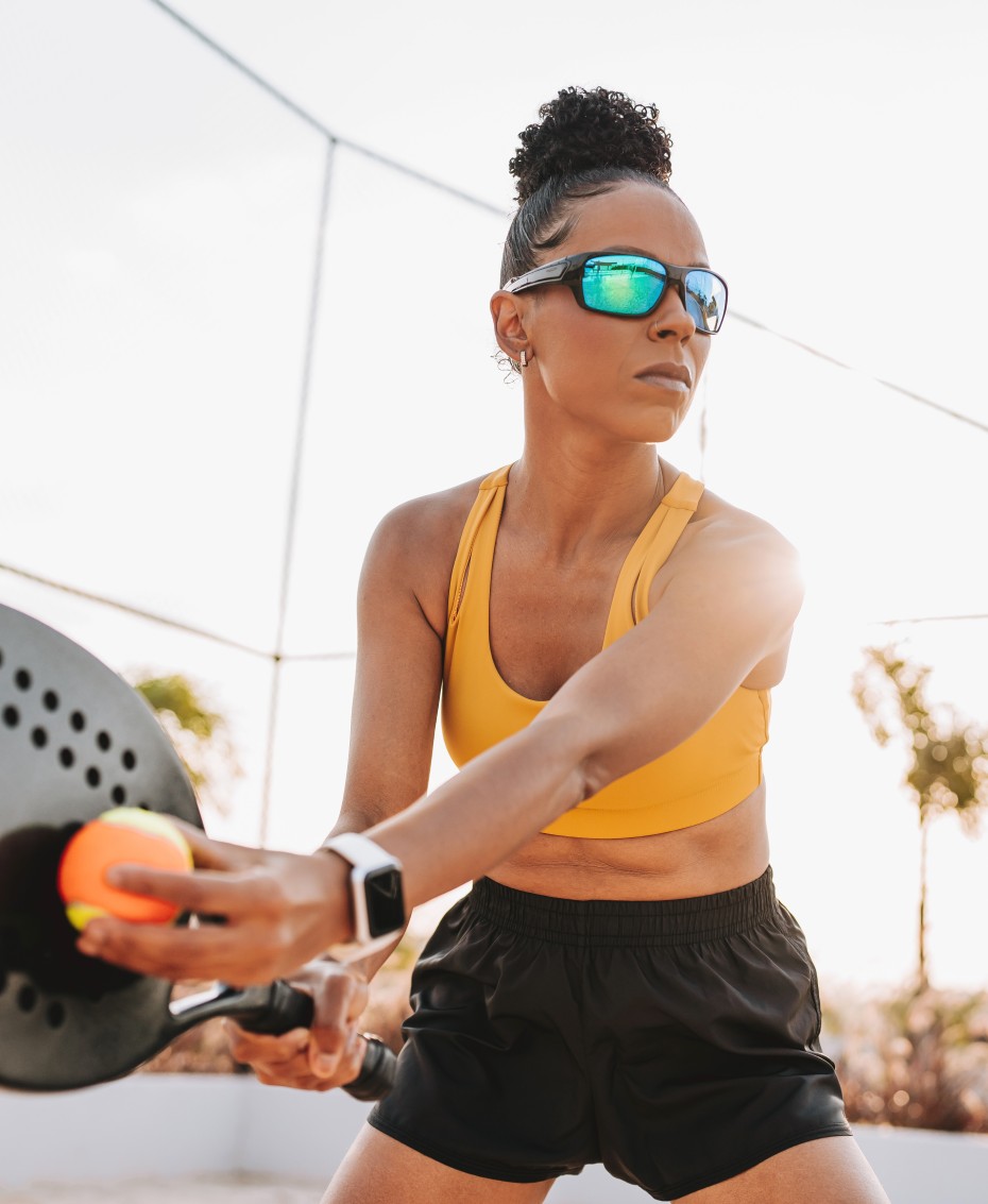 Frau mit Sportbrille beim Padel-Tennis spielen